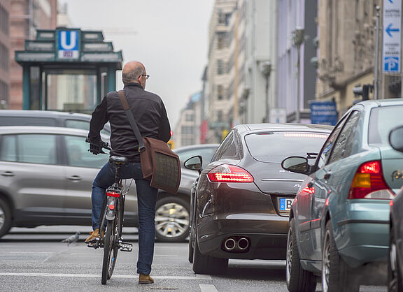 Mann auf einem Rad steht zwischen Autos